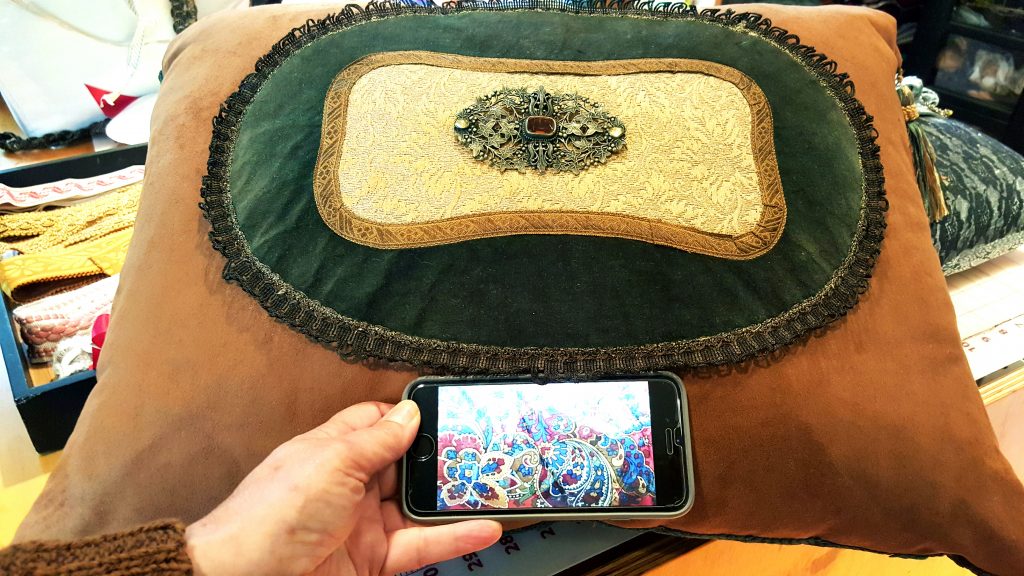 Barbara holding up a photo on her phone of the Ralph Lauren bedding she wanted this pillow for.